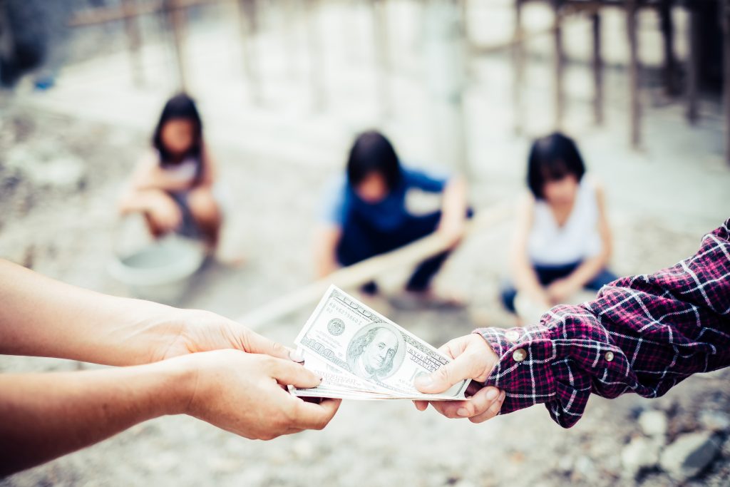 Hands exchanging money. Children violence and trafficking from construction work. World Day Against Child Labour concept.